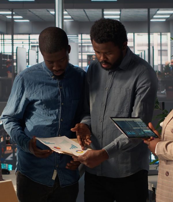 Black leader reviews company strategy with her team members in a modern corporate office, making key business decisions to support organizational growth. Discuss resource allocation. Camera B.