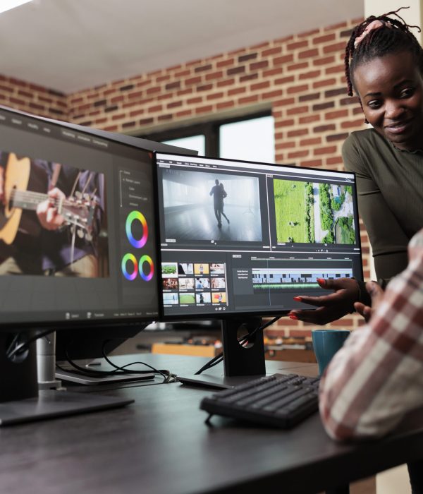 Post production department leader advising colleague to improve colors and frames quality of footage. Creative professional video editors collaborating in order to finish film project upon deadline.